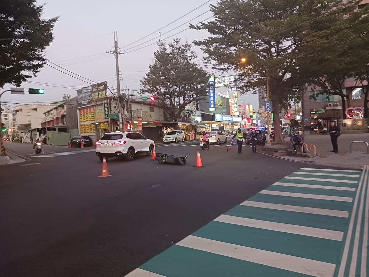 Motocicleta caída en una intersección con conos de señalización y un agente de tránsito al fondo