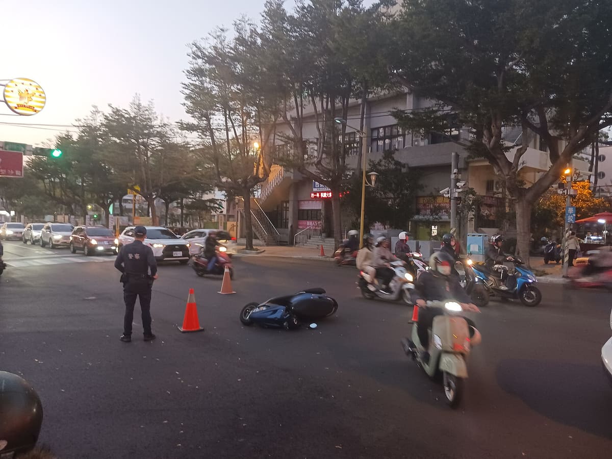 Agente de tránsito junto a conos de señalización mientras otros motociclistas pasan por una vía donde ocurrió un accidente